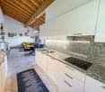 modern kitchen, white cabinets, granite countertops, double sink, stovetop, dishwasher, washing machine, wooden beams, tiled floor, dining area with table and chairs
