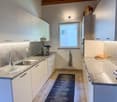 modern kitchen, granite countertops, stainless steel sink, built-in oven, white cabinets, microwave, sink with faucet, towel hanging on the wall, bread on a tray, and electrical outlets