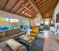 living room with exposed wooden beams, light fixtures, sofa, armchair, coffee table, floor tiles, glass windows, table, chairs