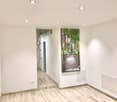 empty hallway, white walls, wooden floor, ceiling lights, poster on the wall