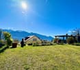 Large open grass lawn, plants, mountains in the background, bright weather