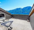 Wooden floor, metal chairs, table, two dumbbells, black railings, mountain view, blue sky