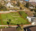 Slope property, hilly terrain, large field, building foundation, other houses in background, mountain view