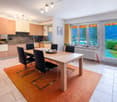 light oak kitchen cabinets, central island, stainless steel oven, dining table, wooden floor, large windows with mountain view