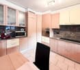 modern kitchen with wooden cabinets, granite countertops, built-in oven and microwave, marble backsplash, tiled floor, black dining chair, marble island, gas stove, and a wine bottle