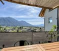 View of mountains, wooden table, chairs, wooden pergola, potted plants