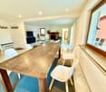 dining room, large wooden table, white chairs, open-plan to living room, fireplace