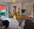 living room with balcony, wooden floor, yellow chair, dining table, TV, radiator, chandelier, potted plant