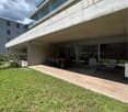 Modern building with glass railings, outdoor dining area, and a grassy lawn