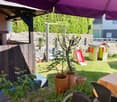 garden with grass, table, chairs, slide, and a small playhouse