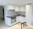 modern kitchen with white cabinets, black countertops, stainless steel appliances, and a dining area with a table and chairs