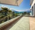 Balcony with glass railings, tiled floor, palm trees, mountain view, sea view