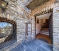 Stone wall entrance, open door, metal mailbox, steps leading to entrance