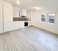 modern kitchen with white cabinets, granite countertops, stainless steel appliances, tiled flooring, two windows