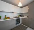 modern kitchen with white cabinets and grey countertops, integrated appliances, open shelving