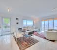 marble flooring, dining table, couch, rug, large windows, balcony, mountain view