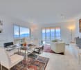 large windows, balcony, dining table, large rug, carpet, sofas, television, artwork