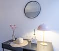 Desk with hat, lamp, flower vase, wine glasses, bottle, welcome card, mirror on wall