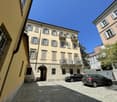 4 story building, beige exterior, multiple balconies, arched entrance, two cars parked in front