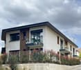 modern 2-story house, white and brown exterior, large windows, balconies, concrete wall, greenery