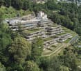 Building on hillside, green roofs, large windows, surrounded by trees, pathway