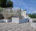 Modern architectural design, concrete walls, brick pavement, greenery, mountains in the background