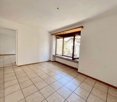 Spacious room with tile flooring, white walls, and a large window providing natural light. The room appears to be empty, with no furniture or decor visible.