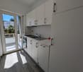 modern kitchen with white cabinets, wooden floor, stainless steel sink, faucet, oven, balcony with glass door
