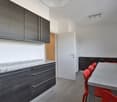 modern kitchen, dark cabinets, granite countertop, red chairs, white door, sink