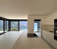 Spacious open-plan living area with large windows offering a scenic view, modern kitchen with built-in appliances, and access to a balcony or terrace.
