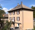 2 story house, yellow exterior, red tile roof, white windows with shutters, balcony, garden