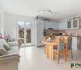 Open-plan living area with dining table, couch, kitchen, and balcony