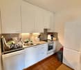 modern kitchen with white cabinets, granite countertop, stainless steel sink, dishwasher, refrigerator, oven, and a granite backsplash