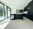 modern kitchen, large windows, balcony, black cabinets, marble countertops, stainless steel appliances