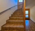 A tiled staircase, a wall with a window and door, and a wooden railing.