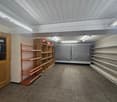 Storage room, empty shelves, white walls, wooden door, fluorescent lights