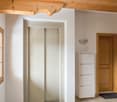 white walls, white elevator, white cabinet, wooden window, wooden ceiling, wooden door