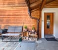 Wooden exterior wall, wooden bench, wooden storage boxes, potted plants, wooden door, tiled floor