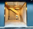 blue exterior doors, wooden staircase, white brick walls, concrete floor, open garage door