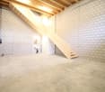 cement floor, white brick walls, wooden staircase, sink