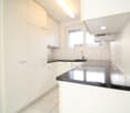 modern kitchen with white cabinets, black countertops, stainless steel sink, faucet, induction cooktop, window