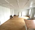 Empty room with wooden floor, white walls, white ceiling, wooden table, chair, rug, windows, doors