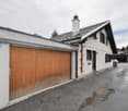 white house, wooden garage, white roof, white pipe on wall, mountains in the background