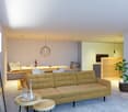 Open-concept living room and kitchen, with a large green sofa, wooden dining table, pendant light fixture, and a kitchen with a patterned backsplash and built-in appliances