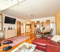 Spacious living room with hardwood floors, red leather sofa, wooden dining table and chairs, built-in cabinets, and a fireplace.