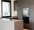 gray countertop, kitchen island, large sink, integrated oven and microwave, modern cabinetry, double sink