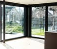 Sliding glass doors, white floor, green outdoor garden, stone wall