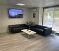 2 black leather couches, coffee table, TV, potted plant, radiator, glass door