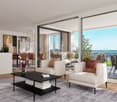 Spacious open-plan living area with large windows and sliding glass doors leading to a balcony with a scenic view. The room features a modern living room setup with a white sofa, armchair, and a black coffee table. The dining area is visible in the backgr