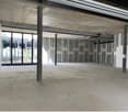 Large open space with concrete floor, exposed ceiling beams, and large windows providing natural light. The space appears to be a commercial or industrial property, likely intended for retail, office, or other commercial use.